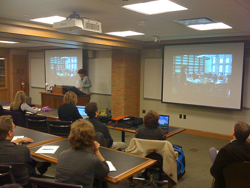 Teacher standing in front of classroom with projector screens