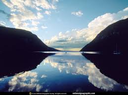 A mountain range reflected in a lake so that the mountains and sky looks duplicated in the lake