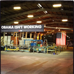 Romney Rebuttal Sign reading Obama Isn't Working hangs in front of American flag in empty factory